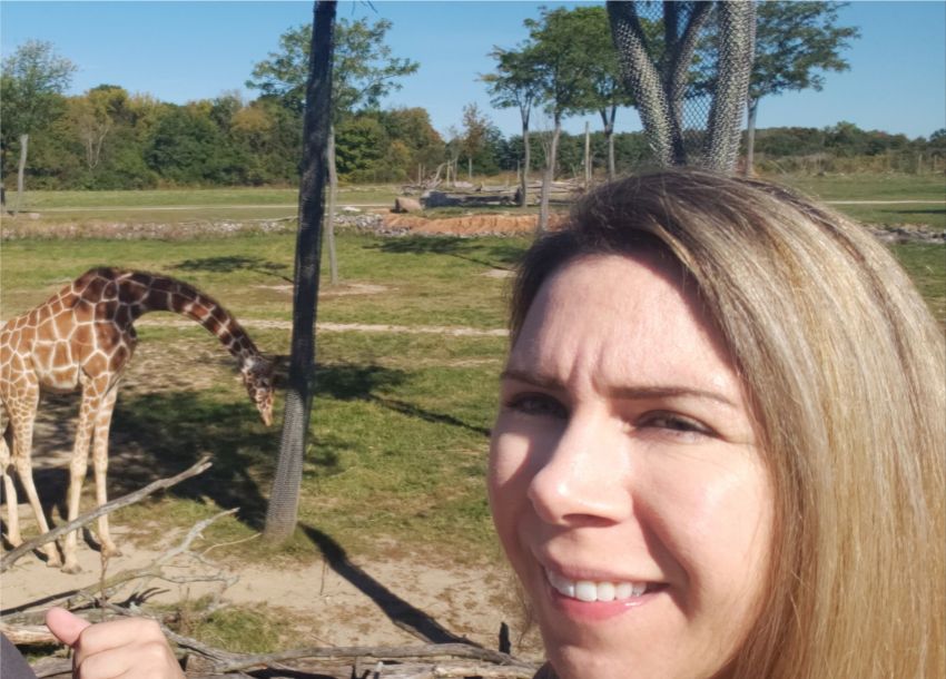 woman standing by giraffe exhibit at zoo